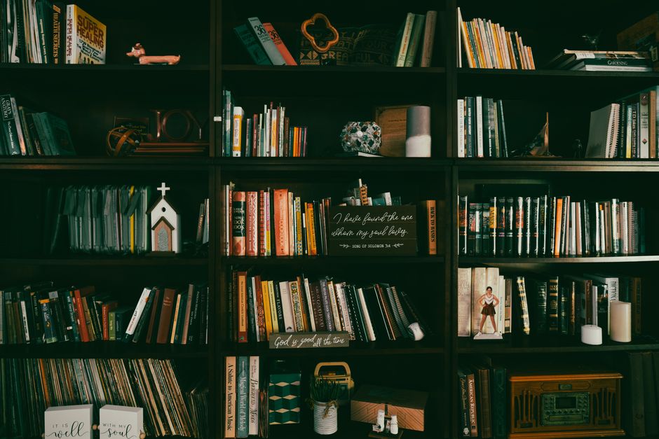 A warm display of a vintage bookshelf filled with books, candles, and home decor items.