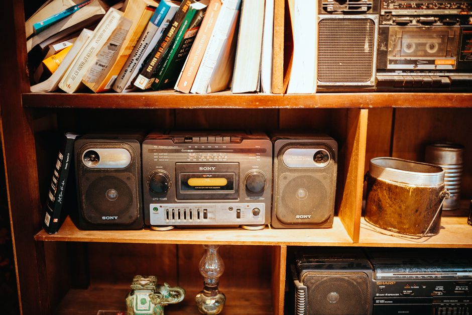 Retro bookshelf featuring a vintage stereo, books, and eclectic decor in a cozy setting.