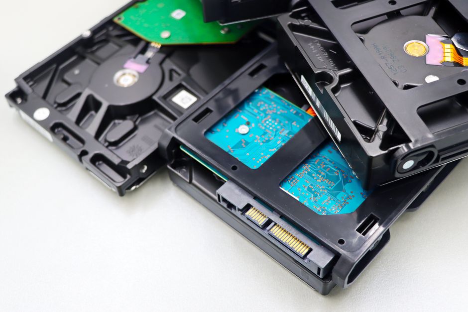 Stack of internal hard disk drives for digital storage on white background.