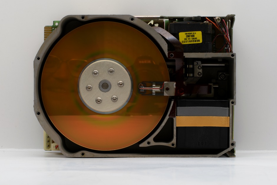 Close-up of an open vintage hard disk drive showcasing its internal components.