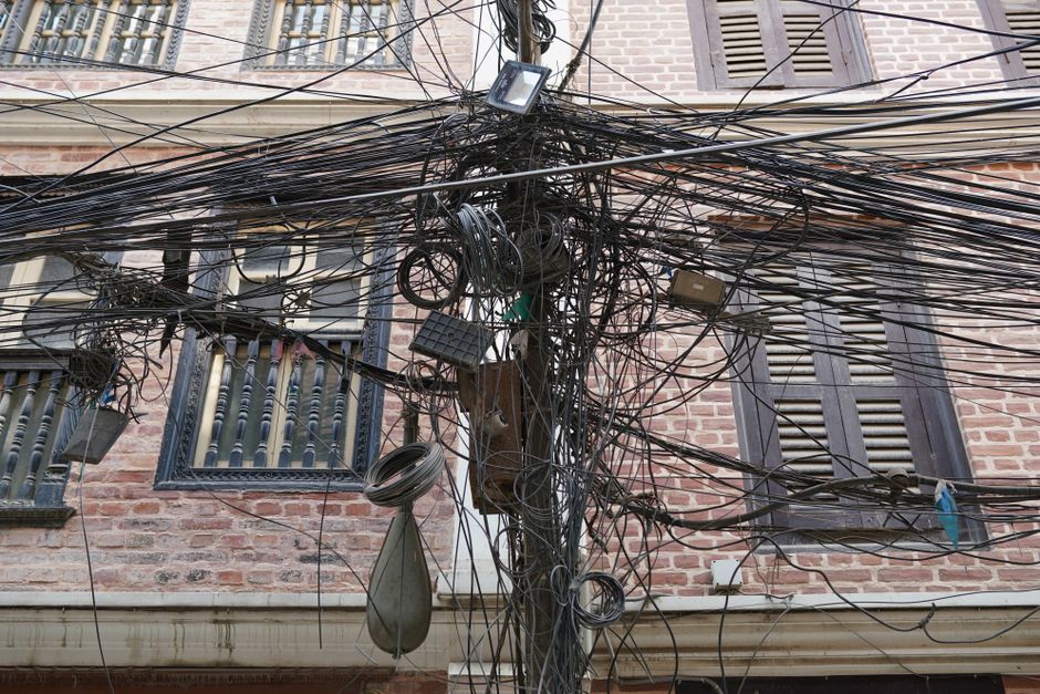 A chaotic array of electrical wires in front of a brick building in Kathmandu, Nepal.